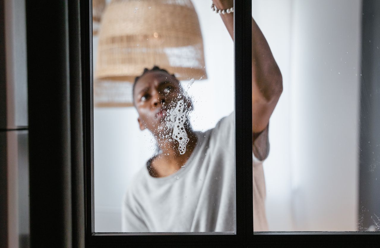 services-03 An adult male cleaning a glass window indoors, focusing on household chores and cleanliness.